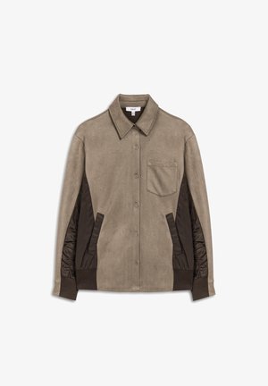 Chemise veste beige avec un tissu principal texturé et des côtés rembourrés marron foncé, dotée d'une poche poitrine et d'un col structuré.