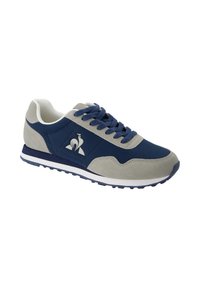 Zapatillas deportivas en azul marino y gris con parte superior de ante y sintético, detalles texturizados, ojales en forma ovalada y suela blanca. Logo en el lateral.