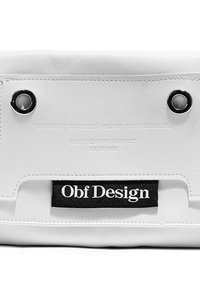 Bolso de mano de cuero blanco con ojales plateados, texto en relieve y una etiqueta de logo negra. Textura suave con detalles de diseño minimalista.