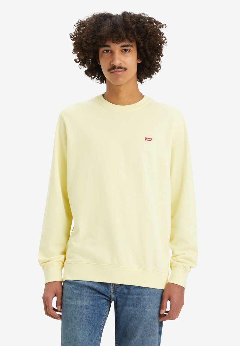 Lichtgele sweater met lange mouwen en een ronde halslijn, met een klein rood Levi's logo op de borst. Zachte stofstructuur.