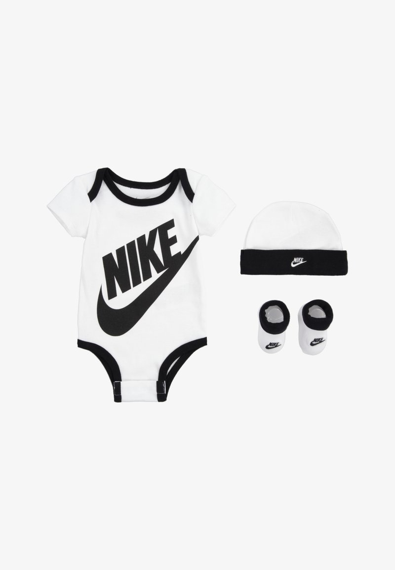 Bela bombažna enodelnica z črnimi robovi in velikim logotipom "NIKE", v kompletu s usklajenim črno-belih klobukom in nogavicami z logotipom Nike.