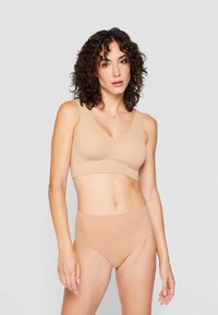 Beige seamless bralette with a v-neck design and wide straps, paired with high-waisted matching briefs, both made of smooth, stretchy fabric.