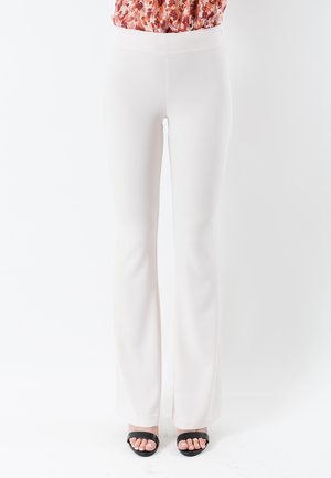 Pantaloni bianchi svasati con texture liscia, design a vita alta e gamba intera, abbinati a sandali neri con cinturini.