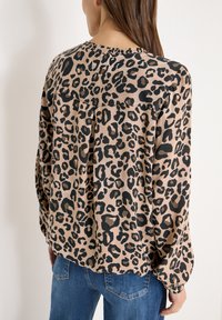 Leopardenmuster-Bluse in Beige und Schwarz mit rundem Ausschnitt, langen Ärmeln und lockerem Schnitt mit einer Rückenfalte.