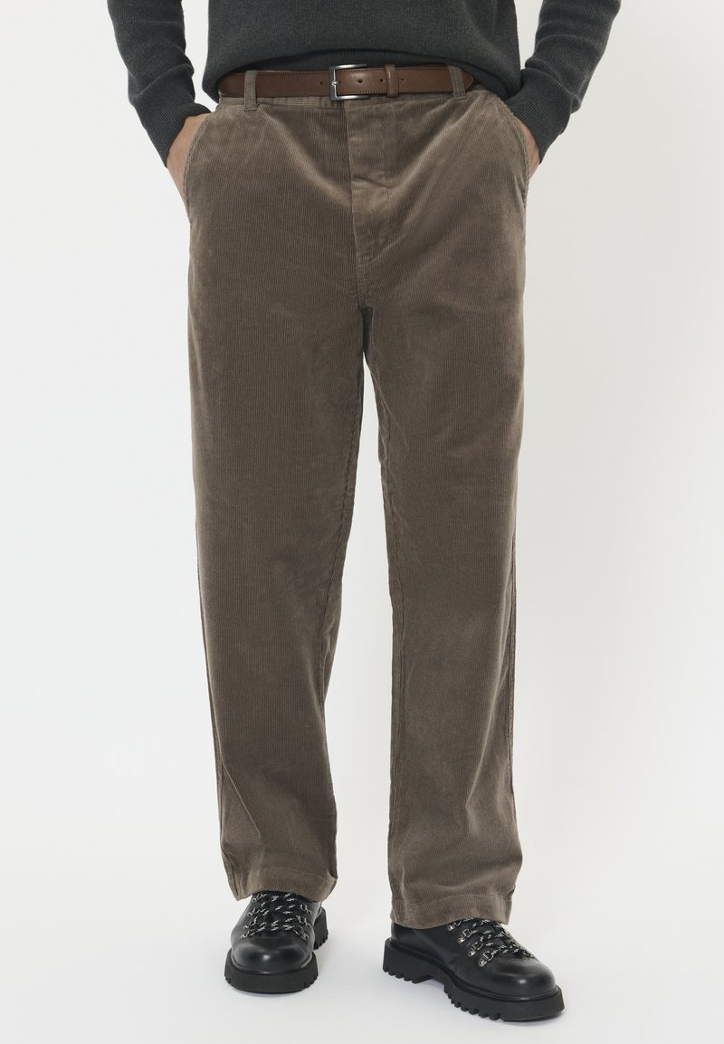 Bruine corduroy broek met een rechte pijp, voorzien van verticale ribbels, voorplooien en zijzakken, gecombineerd met een leren bruine riem.