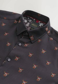 Camicia a fantasia scura con un piccolo motivo di renna, realizzata in tessuto tessuto con una sottile trama geometrica e colletto con bottoni.