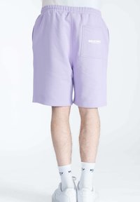 Lavender korte broek gemaakt van zachte stof met een elastische tailleband, voorzien van een achterzak en een witte logo-afdruk op de zak.