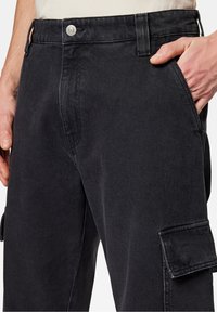 Pantaloni in denim neri con design a gamba dritta, tasca laterale cargo e chiusura con bottone in vita. Tessuto testurizzato con cuciture sottili.