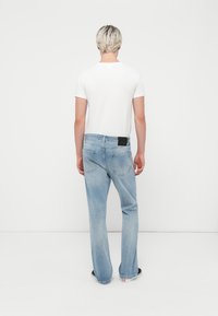 Jeanși din denim de un albastru deschis, cu o croială relaxată, având buzunare din spate cu detalii de cusătură subtile. Asortați cu o cămașă albă simplă, cu mânecă scurtă.
