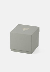 Kvadratisk gaveæske i tekstureret lysegrå materiale, med et guld trekantet logo på låget til branding.