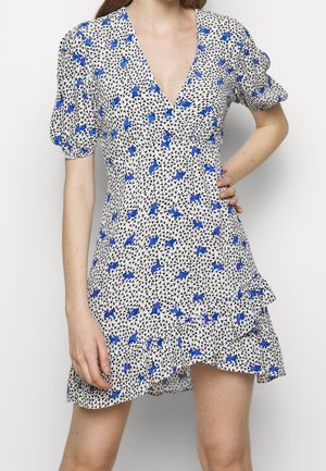 Vestido de manga corta en una tela blanca con patrones florales azules y abstractos en negro. Presenta un escote en V y un dobladillo con volantes.
