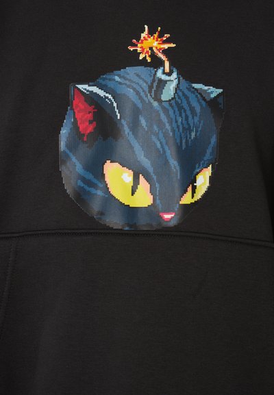 Schwarzer Pullover mit einem Pixel-Art-Design von einer schwarzen Katze mit gelben Augen und roten Ohren, gekrönt von einer Grafikanimation einer Bombe und Funken.