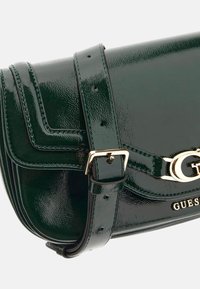 Borsa a tracolla in pelle verniciata verde con dettagli in oro, dotata di chiusura a pattina, tracolla regolabile e logo del brand impresso sul davanti.