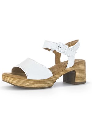 Białe skórzane sandały z szerokim paskiem z przodu, regulowanym paskiem na kostkę i drewnianym obcasem w formie bloku z poziomymi rowkami.