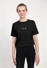 Sort kortærmet t-shirt med et minimalistisk hvidt grafisk design af en nøgle med en cirkel og firkant, lavet af bomuldsmateriale.