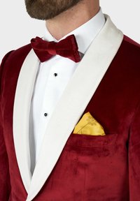 Burgunderfarbener Samt-Smokingjacke mit weißen Satin-Schalkragen, kombiniert mit einer roten Samtschleife und einem goldenen Taschentuch mit floralem Muster.