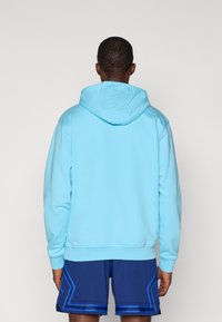 Svetlomodrá mikina s kapucňou a predným vreckom. Hladký materiál, rebrované manžety a lem. Spárované s námorníckymi šortkami s modrými akcentmi.