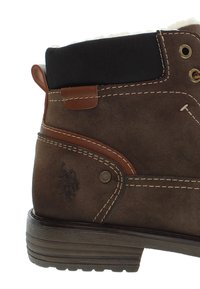 Hnědé kožené kotníkové boty se semišovým povrchem, gumovou podrážkou, hnědými akcenty, kovovými očky a černým látkovým límcem. Logo je raženo na straně.