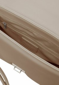 Beige handtas interieur met een gladde textuur; heeft een ritsvak en een vlak label. De hardware is zilverkleurig.