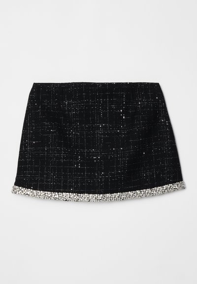 Crna mini suknja s teksturiranim uzorkom, ukrašena srebrnim kristalnim rubom na donjem dijelu. Izrađena od tkanine s tkanim uzorkom.