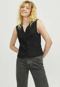 Crna bezrukavna prsluk s V-izrezom, pet dugmadi i dva prednja dzepa. Tkanina izgleda glatko s lagano strukturiranim krojem.