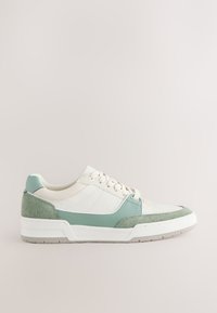 Baskets basses blanches et vert pâle avec des panneaux en daim et cuir, lacets blancs, et une semelle blanche texturée.