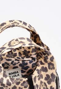 Torebka typu tote w panterkę w kolorze brązowym i czarnym. Elastyczny materiał z krótkimi uchwytami i zamkiem błyskawicznym. Metka z napisem "BIMBA Y LOLA."