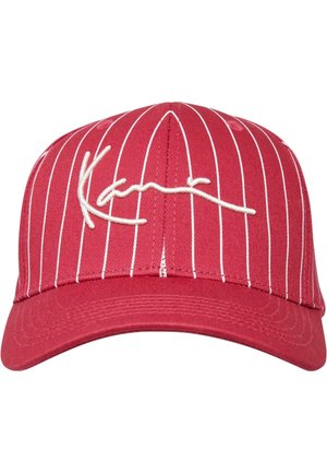 Rød baseballkasket med hvide striber, der har en broderet signatur på forsiden. Klassisk facon med en buet skygge og tekstiler med struktur.