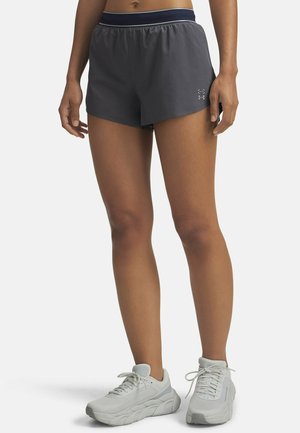 Korta grå sportshorts med resårmidja och sidoklipp. Har en diskret logotyp vid fållen, kombinerat med vita sneakers.