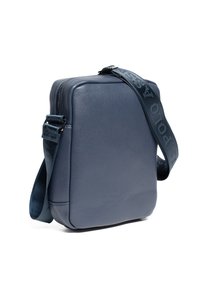 Modrá kožená crossbody taška s texturovaným povrchem, obdélníkovým tvarem a vzorovaným popruhem. Obsahuje horní zip pro uzavření.