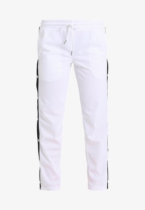 Biele športové nohavice s voľným strihom, čiernymi bočnými panelmi a patentkami. Obsahujú elastický pás s šnúrkou na stiahnutie.