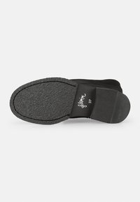 Semelle de chaussure noire avec une surface texturée, bout arrondi et petit talon. Présente un bord surpiqué et une étiquette de taille imprimée sur le côté intérieur.