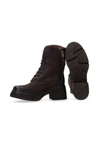 Bottines en cuir marron avec un laçage à l'avant, fermeture éclair sur le côté et talon bloc. Tige texturée et semelle en caoutchouc avec des détails en motif circulaire.