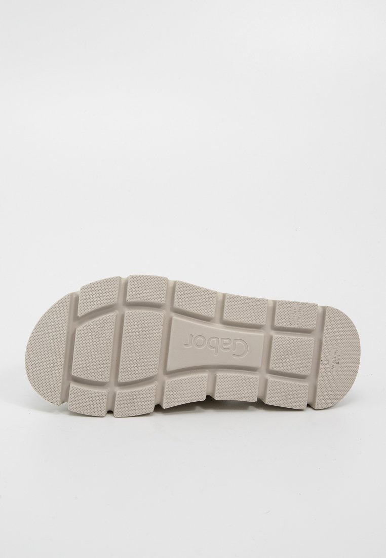 Lichtbeige schoenzool met een gestructureerd oppervlak, voorzien van een rasterpatroon voor grip en een ronde neus. Logo zichtbaar in het midden.