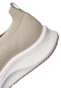 Béžová pletená slip-on teniska s poutkem, prodyšným svrškem a tlustou bílou polstrovanou podrážkou s texturovaným gripem.