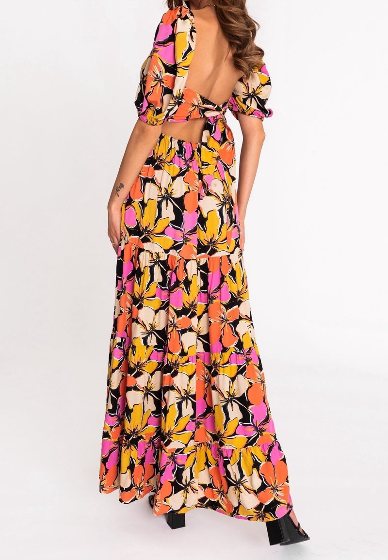 Robe florale avec des manches bouffantes, un dos nu et une jupe à volants. Présente des couleurs vives comme l'orange, le rose et le jaune sur un fond noir.