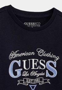 Marineblaues Sweatshirt aus Bio-Baumwolle, mit gesticktem weißen und hellblauen Text, Rundhalsausschnitt mit gerippten Details.