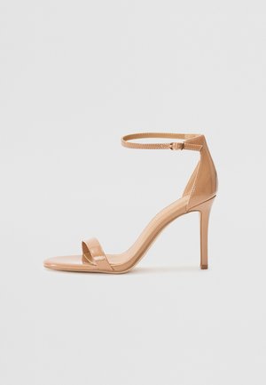 Nude patentläder högklackad sandal med en smal ankelrem, öppen tå-design och en minimalistisk silhuett.
