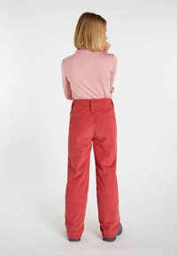 Rote Cordhosen mit hoher Taille und weitem Bein, die eine sichtbare vertikale Rippstruktur aufweisen. Das Design beinhaltet Gürtelschlaufen und eine Gesäßtasche.