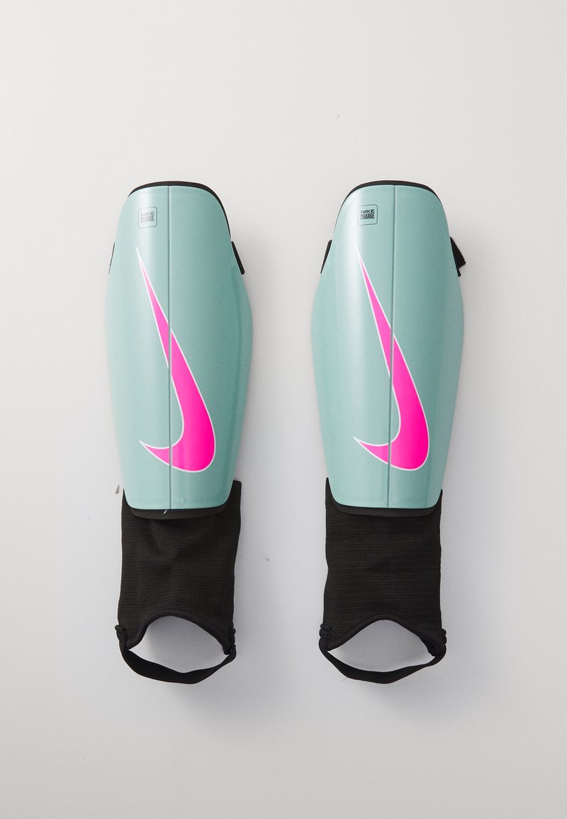 Nike scheenbeschermers, lichtgroene plastic behuizing, opvallende roze swoosh, met zwarte elastische mouwen aan de onderkant voor een veilige bevestiging.