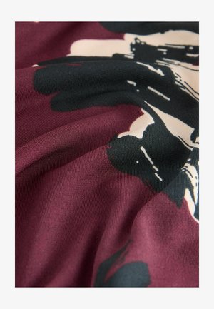 Bordeauxfarbener Stoff mit glatter Textur, der ein schwarz-creamfarbenes abstraktes Blumenmuster aufweist. Der Stoff wirkt leicht und fällt weich.