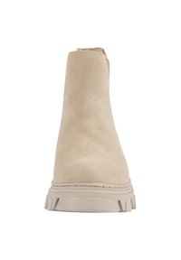 Bottine en daim beige avec une texture lisse, bout rond et semelle épaisse et robuste. Présente des coutures minimales et un design à enfiler.