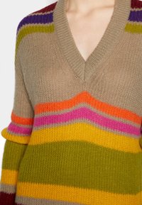 Beige V-ringad tröja i ullblandning med flerfärgade horisontella ränder i orange, rosa, gult, grönt och lila. Strukturerad stickning.