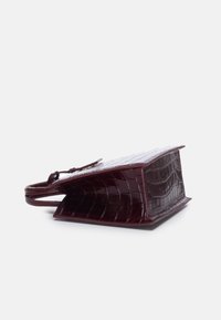 Borsa bordeaux in pelle con effetto coccodrillo, dal design strutturato, base piatta e manici corti. Presenta una finitura lucida e bordi definiti.