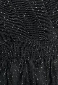 Tecido plissado preto com uma cintura franzida, apresentando detalhes metálicos espalhados para adicionar textura e detalhe visual.