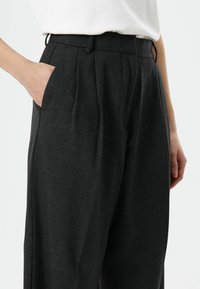 Antracietgrijze broek met een getailleerde pasvorm, geplooide voorkant en zijzakken. Gemaakt van een gestructureerde stof, met een hoog tailleontwerp.