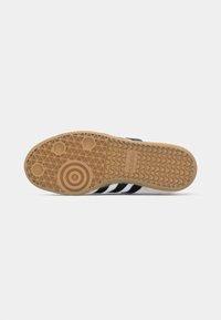 Sola de ténis Adidas preto e branco com sola de borracha de goma, padrões de piso circulares e ondulados, e logótipo da Adidas na área do calcanhar.