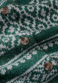 Zöld és fehér mintás kötött szövet, három barna, kerek, négylyukú gombbal diagonális elrendezésben.