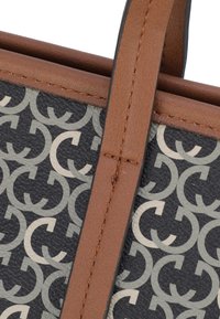 Accenti in pelle marrone su un tessuto stampato con logo nero e crema; presenta una finitura testurizzata e un dettaglio di cucitura a contrasto.