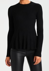 Svart ribbad långärmad topp med figurnära överdel och plisserad nederkant, tillverkad av ett texturerat stickat tyg. Perfekt för att använda som lager eller för avslappnad stil.